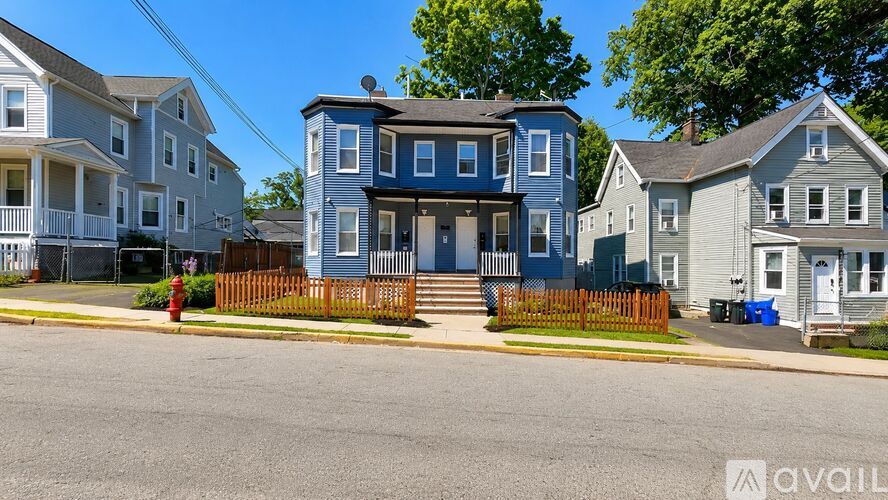 A blue house with a white fence in front of it.