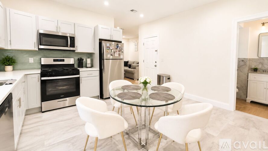 A modern kitchen with a glass dining table and white chairs.
