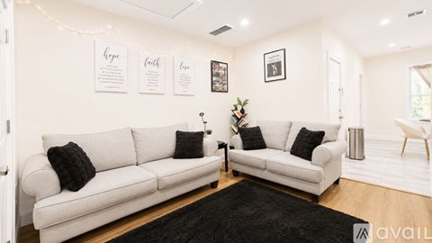 A living room with two white couches and a black rug.