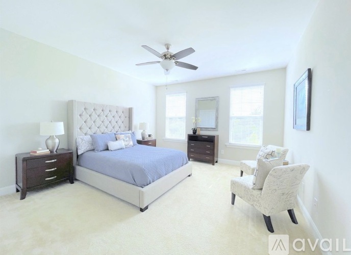 A bedroom with a large bed, a chair, and a ceiling fan.