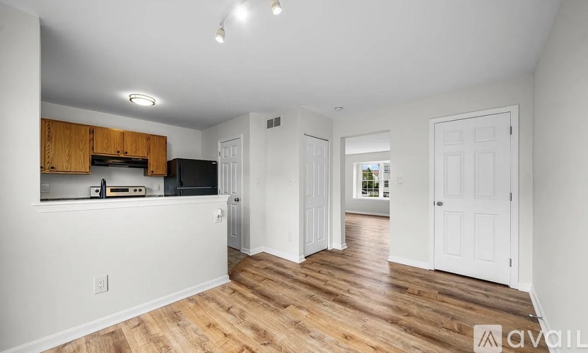 A spacious living room with wood flooring and white walls.
