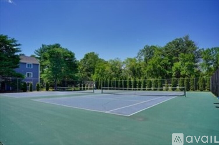 A tennis court surrounded by trees and a building.