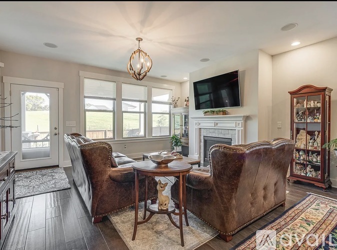 A living room with a brown leather couch, a wooden coffee table, and a flat screen TV mounted on the wall.
