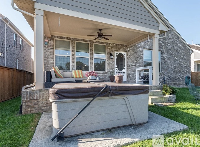 A hot tub is on a patio with a ceiling fan.
