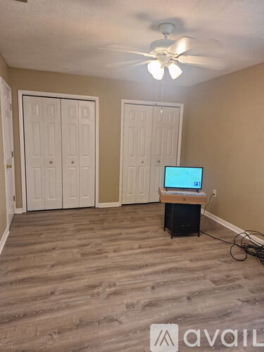 A room with a ceiling fan and a television on a stand.