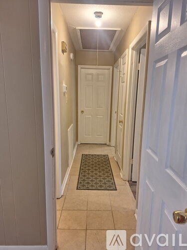 A hallway with a rug on the floor and a door on the right.