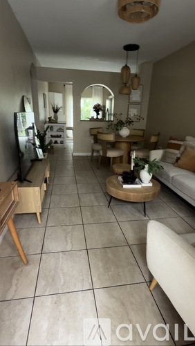 A living room with a couch, a chair, and a dining table.