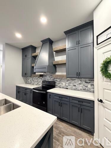 A kitchen with grey cabinets and a white countertop.