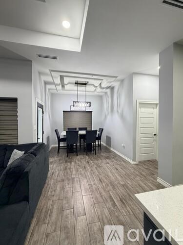 A modern living room with a black couch and a dining table with chairs.
