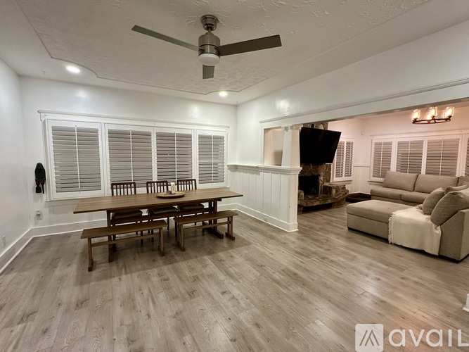 A spacious room with a wooden table and chairs, a couch, and a ceiling fan.