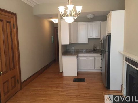 A kitchen with white cabinets and a black refrigerator.