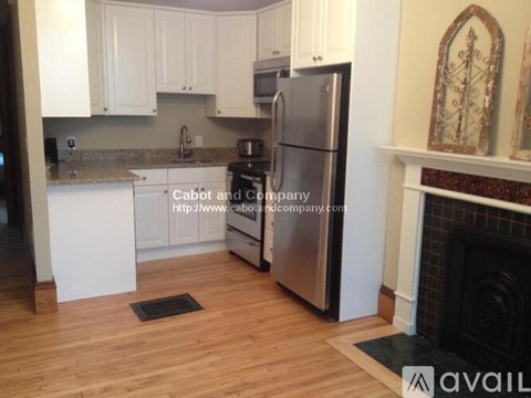 A kitchen with white cabinets and a stainless steel refrigerator.