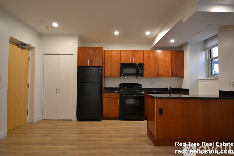 A kitchen with wooden cabinets and black appliances.