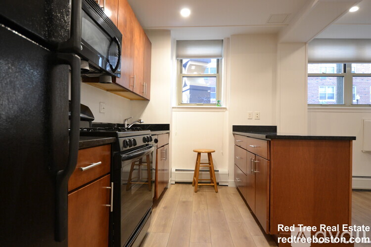 A kitchen with black appliances and wooden cabinets.