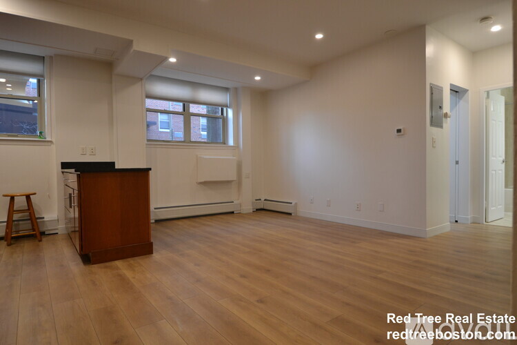 A spacious room with wooden flooring and a bar area.