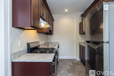 A kitchen with a granite countertop and dark brown cabinets.