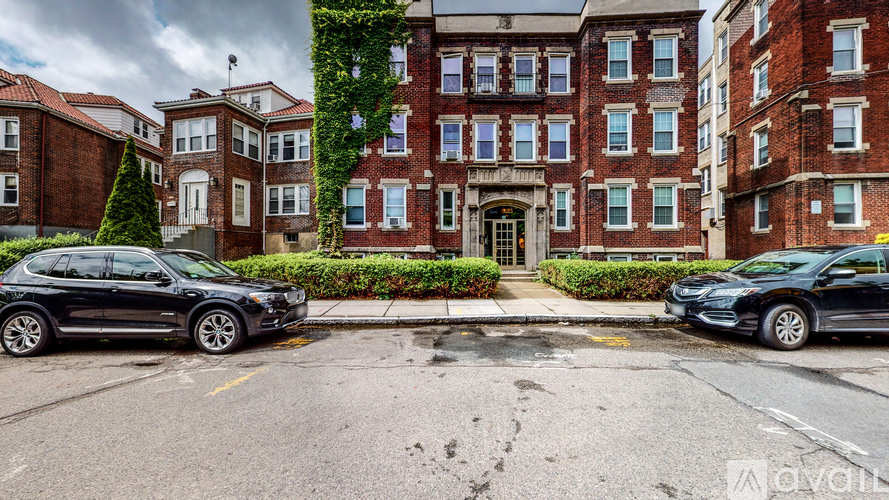 Two cars are parked in front of a red brick building.