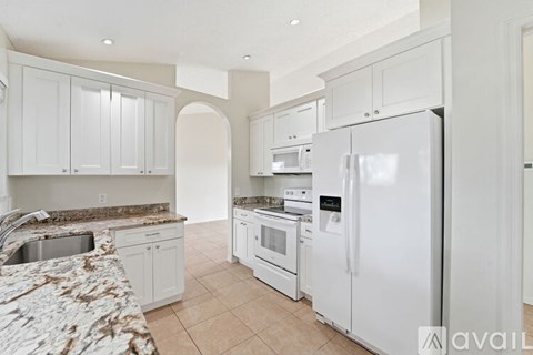 A kitchen with white appliances and cabinets.