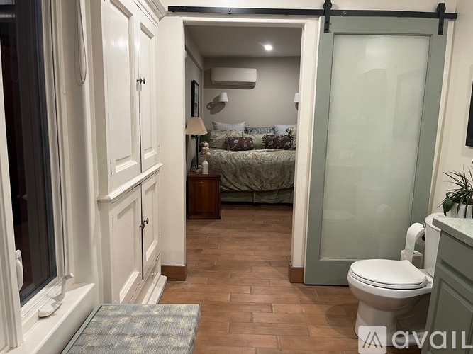 A small bedroom with a bed, nightstand, and a toilet.