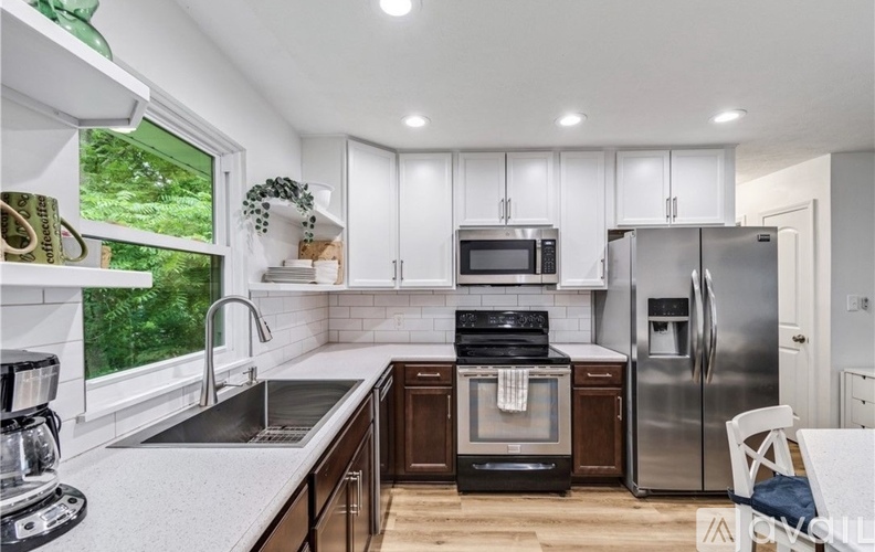 A modern kitchen with a stainless steel refrigerator, microwave, and oven.