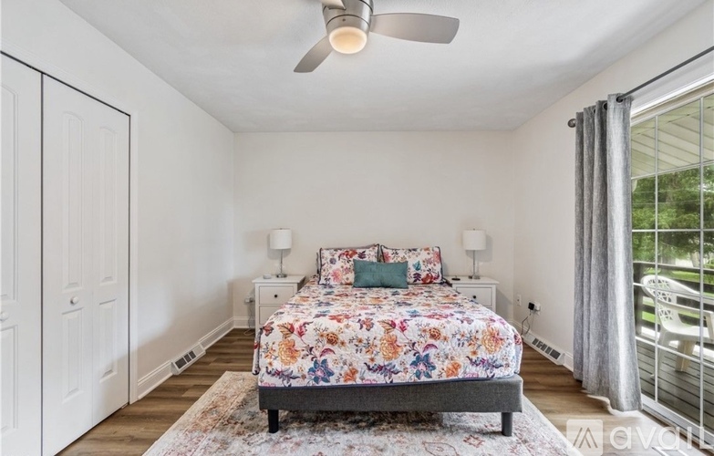 A bedroom with a floral bedspread and a ceiling fan.