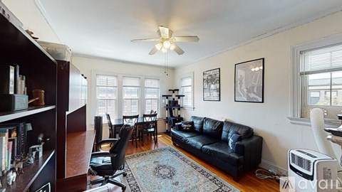 A living room with a black couch and a ceiling fan.