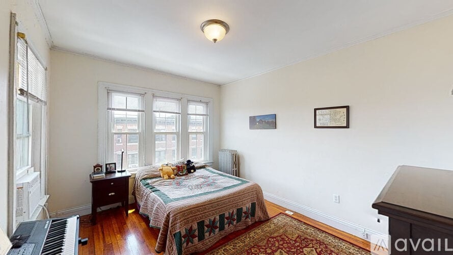 A bedroom with a bed, a piano, and a window.