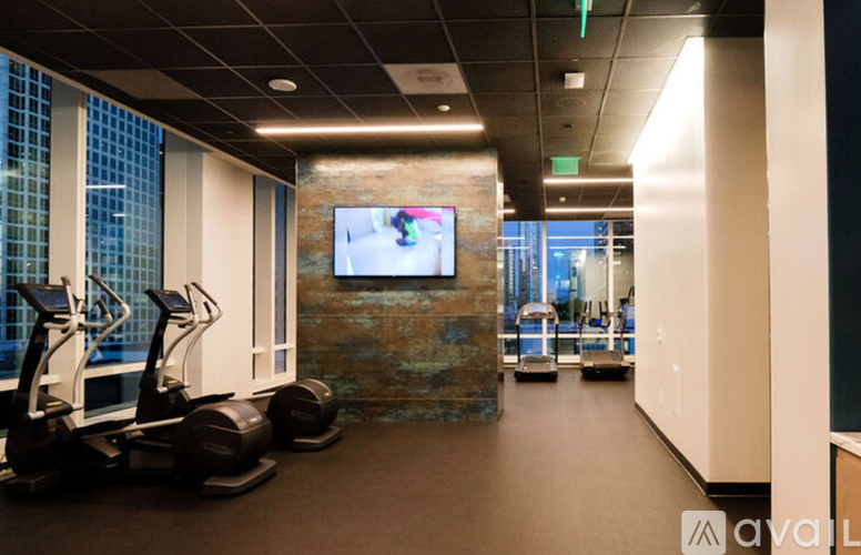 A gym with treadmills and a television mounted on the wall.