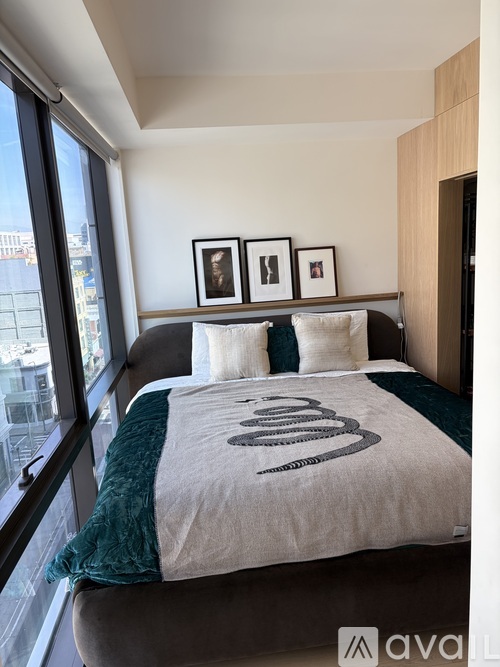 A bedroom with a bed, a window, and three picture frames on the wall.