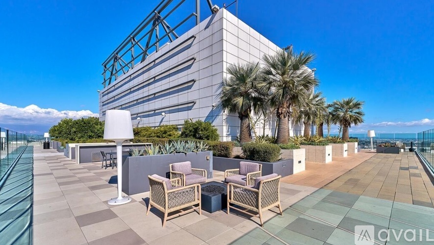 A modern building with a glass facade and a terrace with chairs and tables.