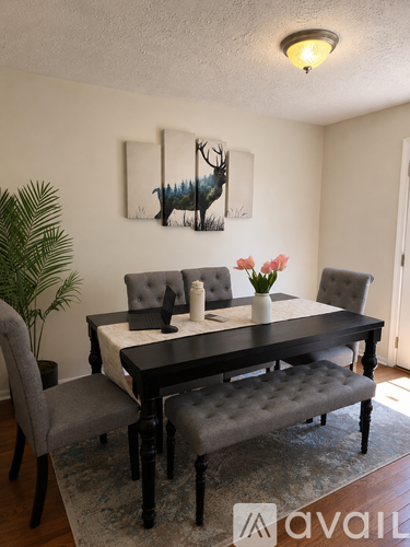 A dining room with a table set for two and a painting of a deer on the wall.