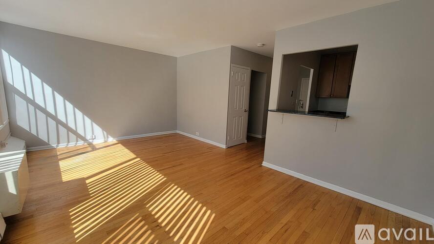 A room with wooden flooring and a window letting in sunlight.