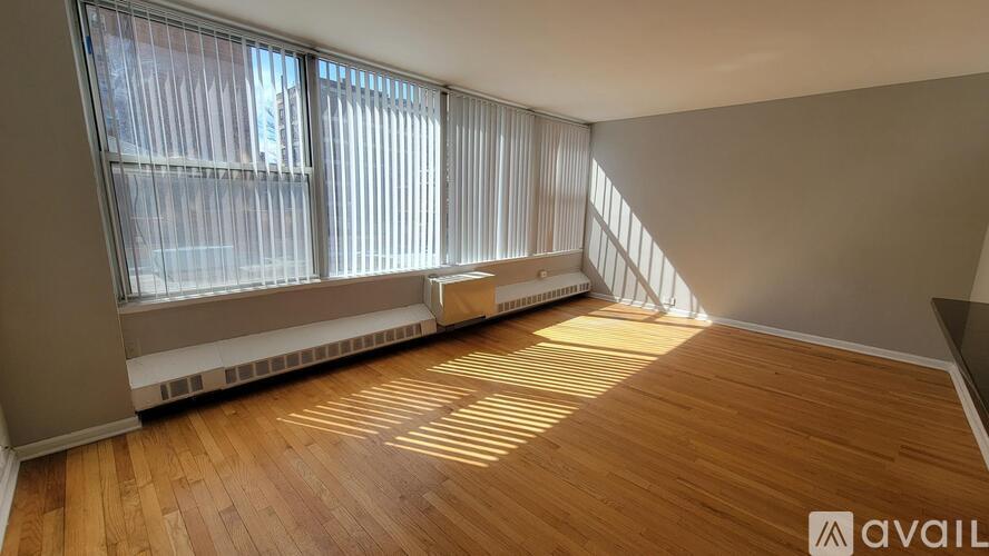 A room with wooden flooring and a window with blinds.
