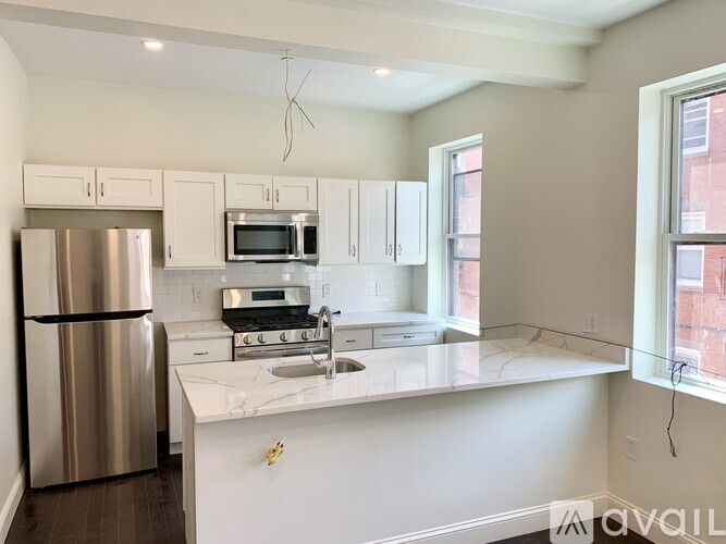 A kitchen with a refrigerator, microwave, oven, and sink.