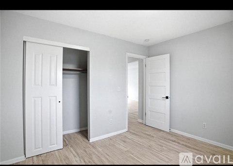 A room with a white door and a wooden floor.