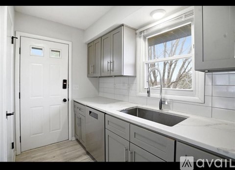 A kitchen with a white door, a window, and a sink.