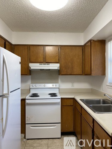 A kitchen with a white refrigerator, white stove, and wooden cabinets.