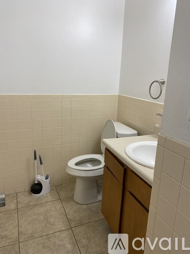 A bathroom with a toilet, sink, and toilet brush.