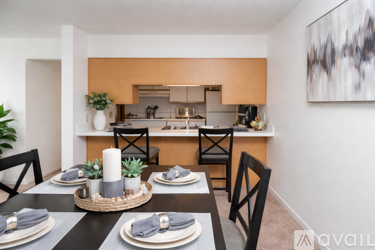 A dining room with a table set for two and a kitchen area in the background.