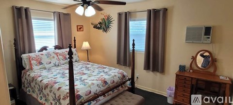 A bedroom with a four poster bed and a ceiling fan.