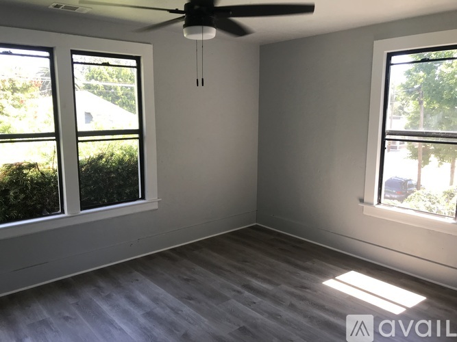 A room with a ceiling fan and two windows.