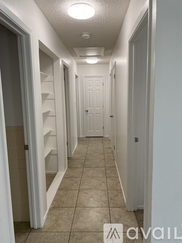 A long hallway with white doors and tiled floors.