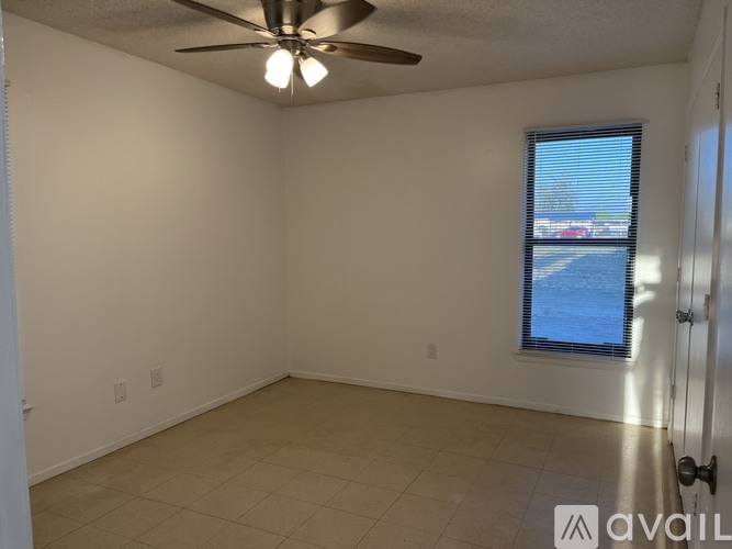 A room with a ceiling fan and a window with blinds.