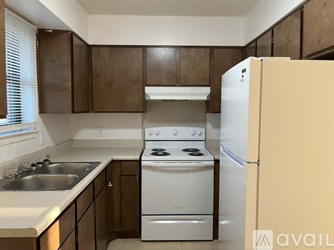 A kitchen with a white stove and refrigerator.