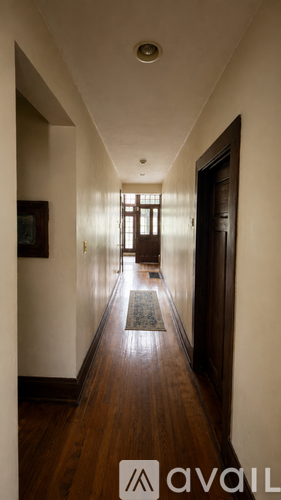 A long hallway with a rug on the floor and a door at the end.