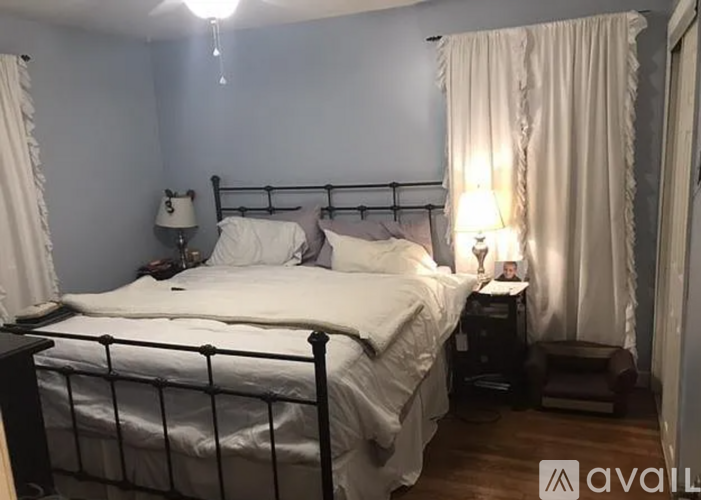 A bedroom with a large bed and a nightstand with a lamp.