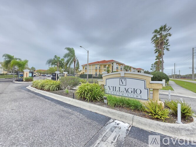 A sign for "Villagio Condominiums" is in front of a building with a cloudy sky in the background.