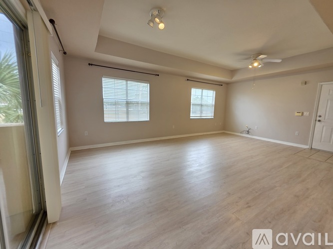 A spacious room with wooden flooring and two windows.