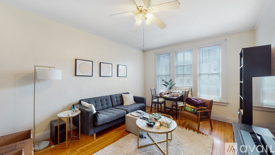 A living room with a grey couch, a coffee table, and a ceiling fan.