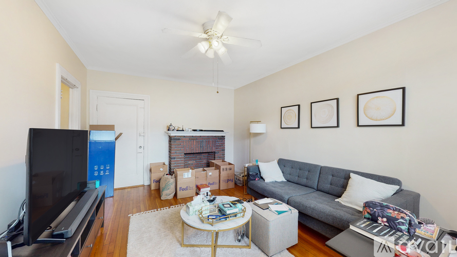 A living room with a grey couch, a television, and a fireplace.
